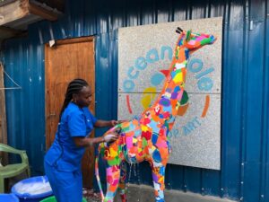 Ocean Sole employee cleaning a Giraffe sculpture